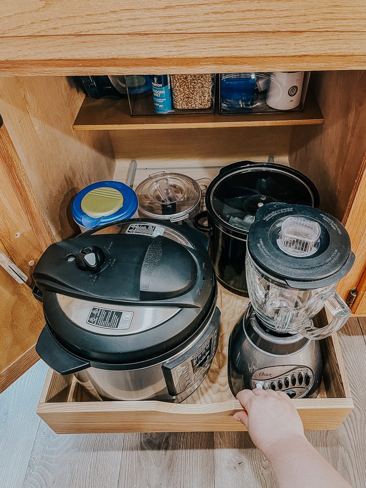 An open kitchen drawer showing a pressure cooker and a blender among other items