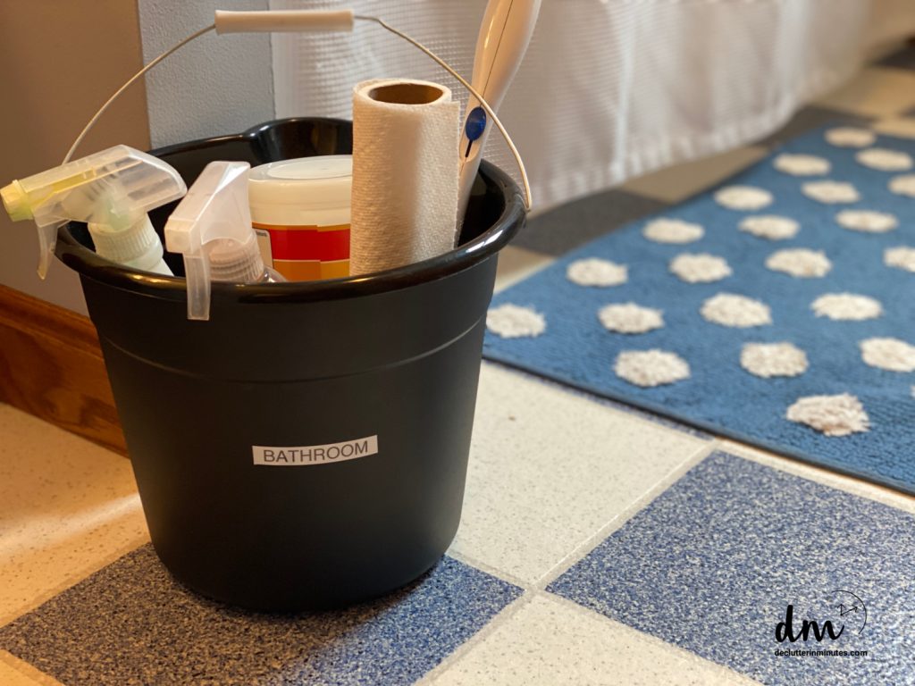 a black bucket filled with cleaning supplies on a bathroom floor