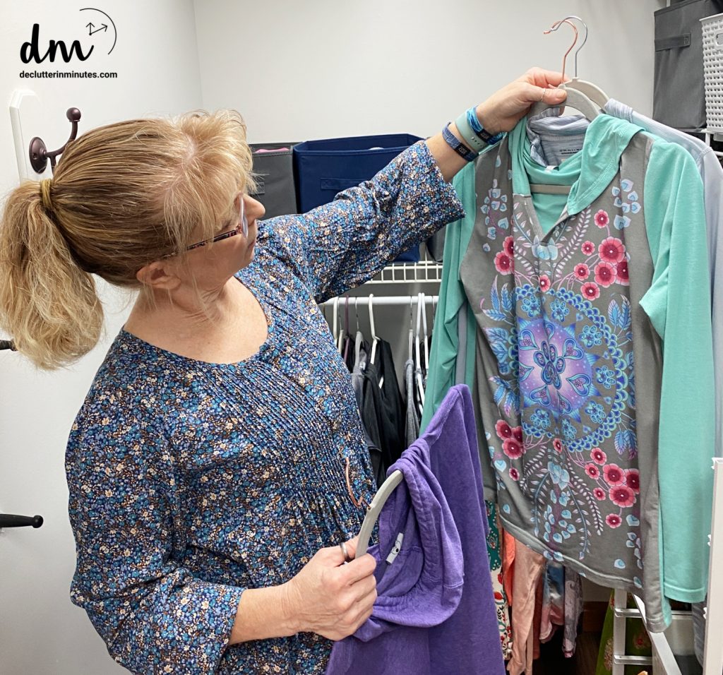 A busy mom holding clothes on hangers in a closet