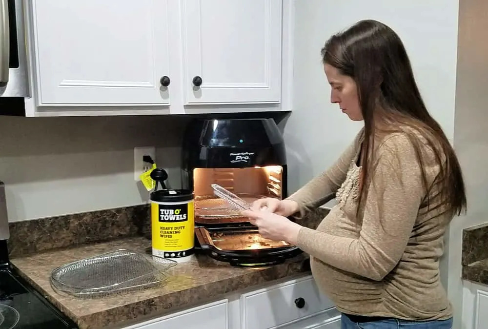 woman cleaning an air fryer with cleaning wipes
