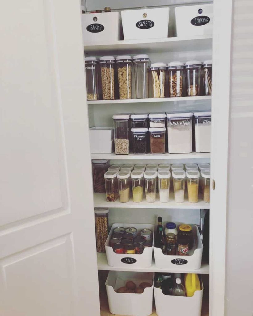 pantry with labeled bins for baking, sweets, and cooking, and clear containers filled with dry goods and spices