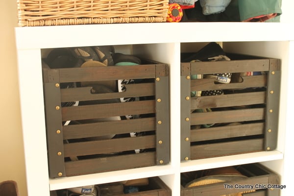 A wooden storage unit with two crates used for storing shoes