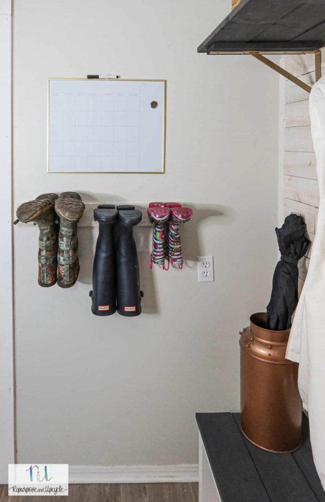 mudroom wall featuring a small white rack holding various boot