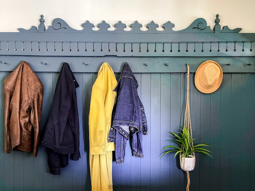 mudroom wall with multiple hooks holding jackets, a denim shirt, and a straw hat