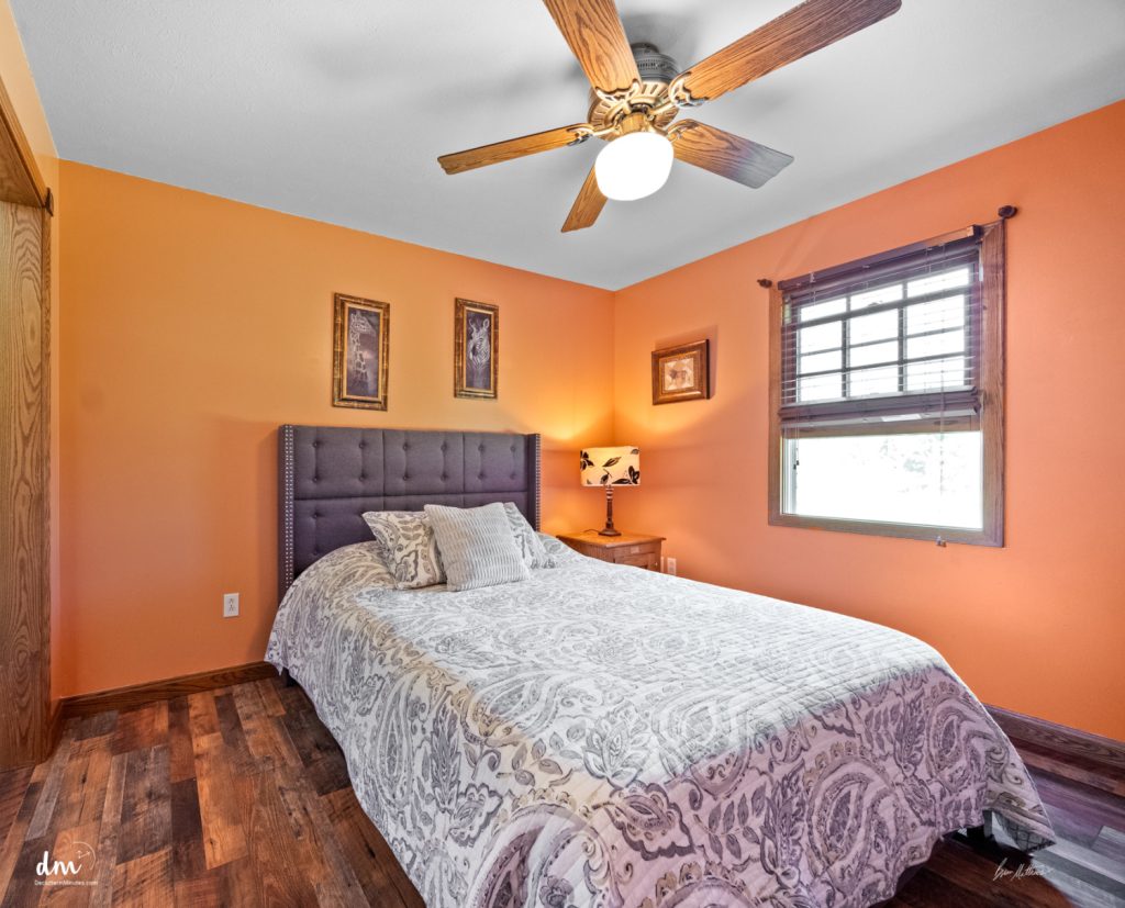 a guest room with a bed and nightstand and orange walls