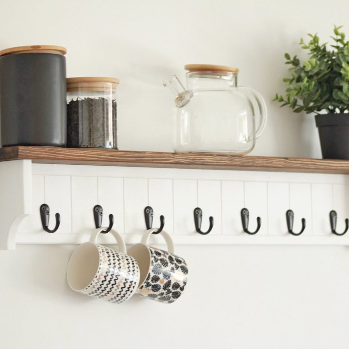 Wall-mounted shelf with hooks holding mugs