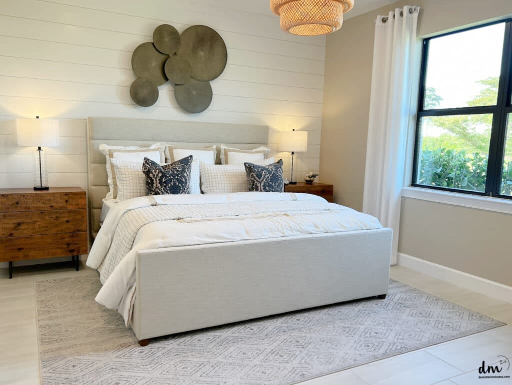 a cozy bed next to a clear nightstand in a lovely white bedroom