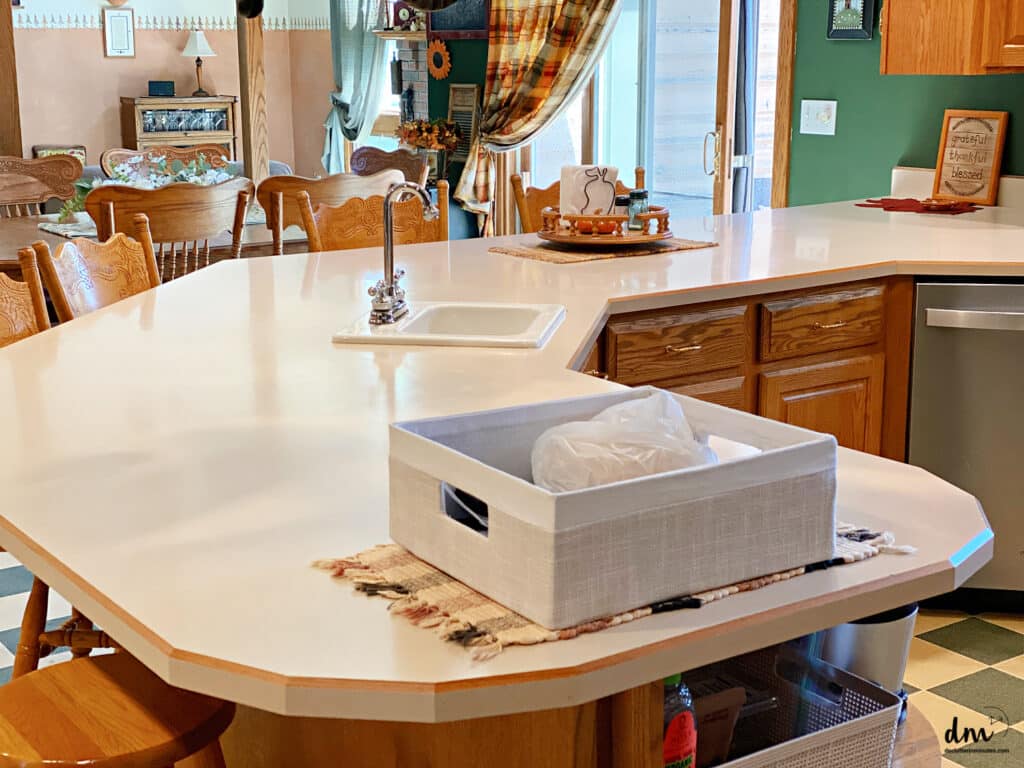 a kitchen counter that is clear with a basket holding random items on the end