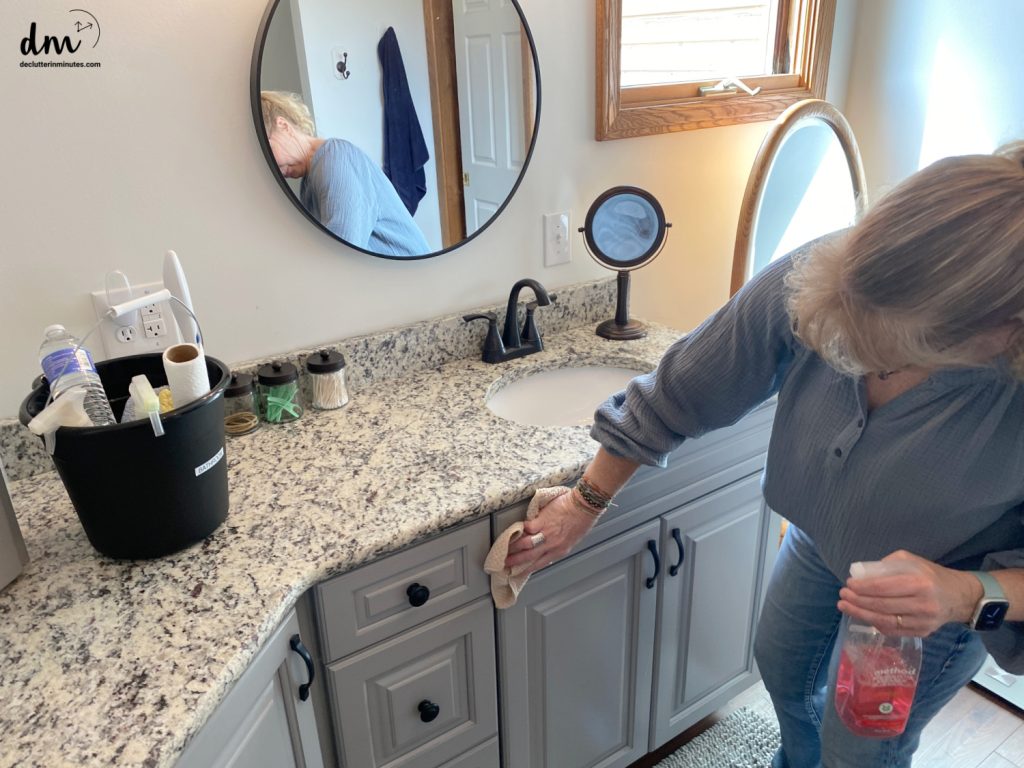 a woman wiping down a bathroom vanity with a rag