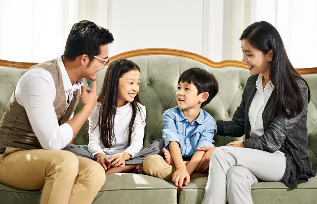 a young family sitting on a couch talking and smiling