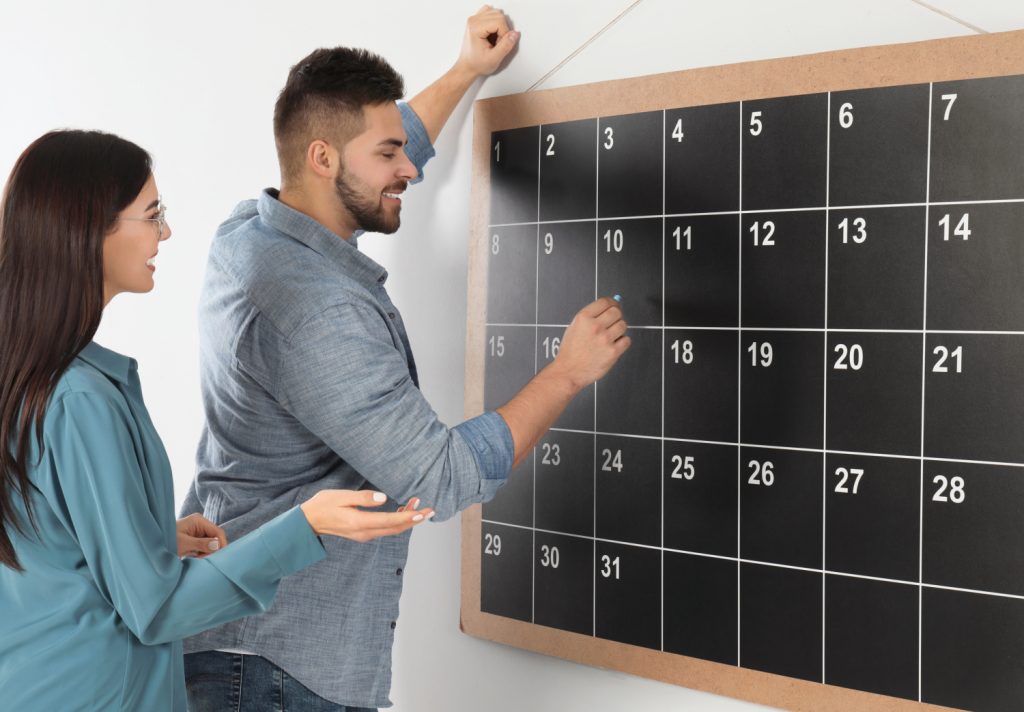 parents filling out a chalkboard calendar in a commend center in a home