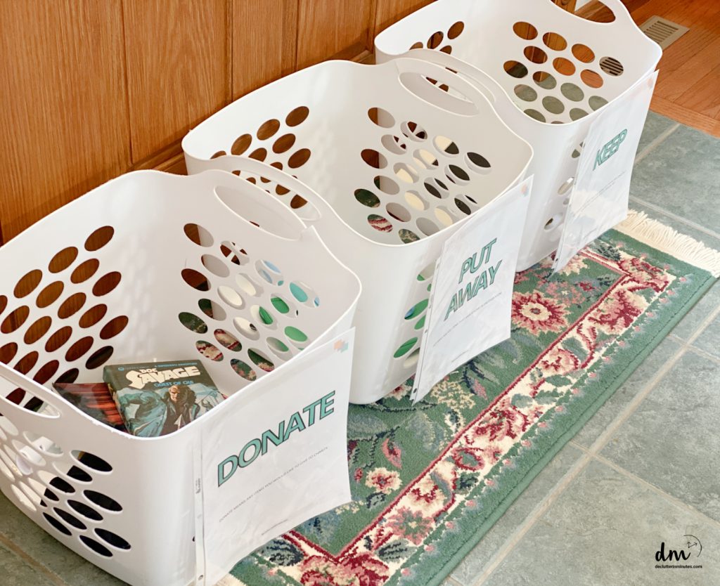 3 white baskets with labels on the floor of a room that is being decluttered