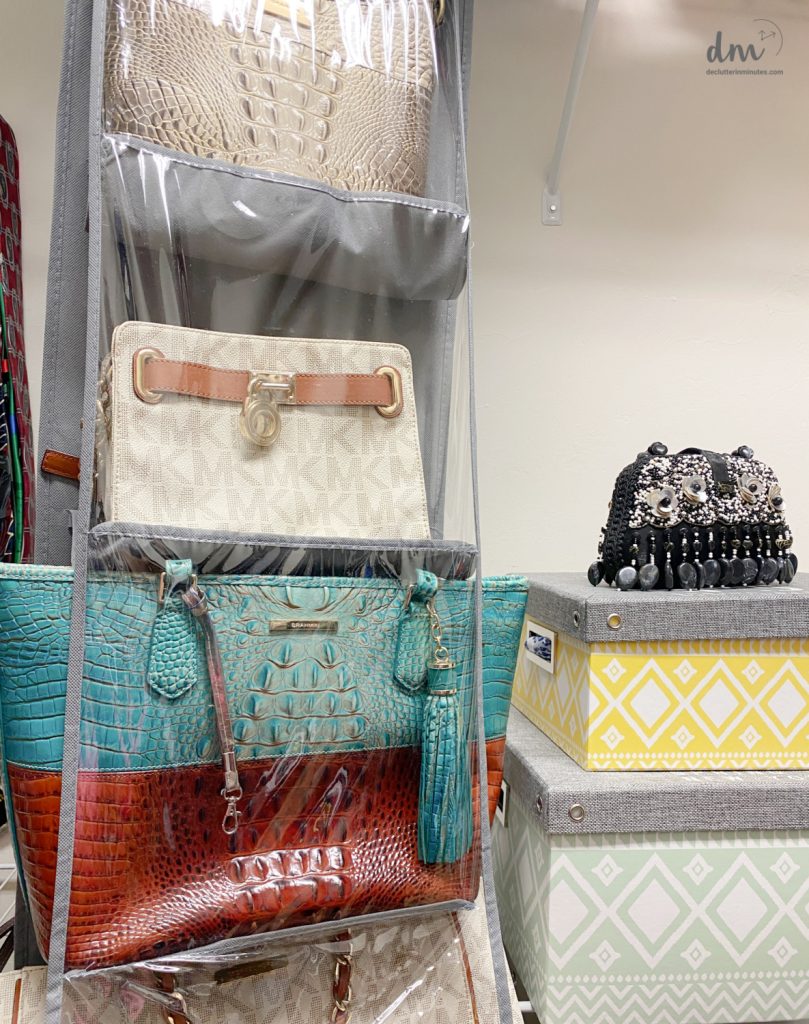 a plastic hanging organizer filled with colorful purses next to hat boxes in a closet