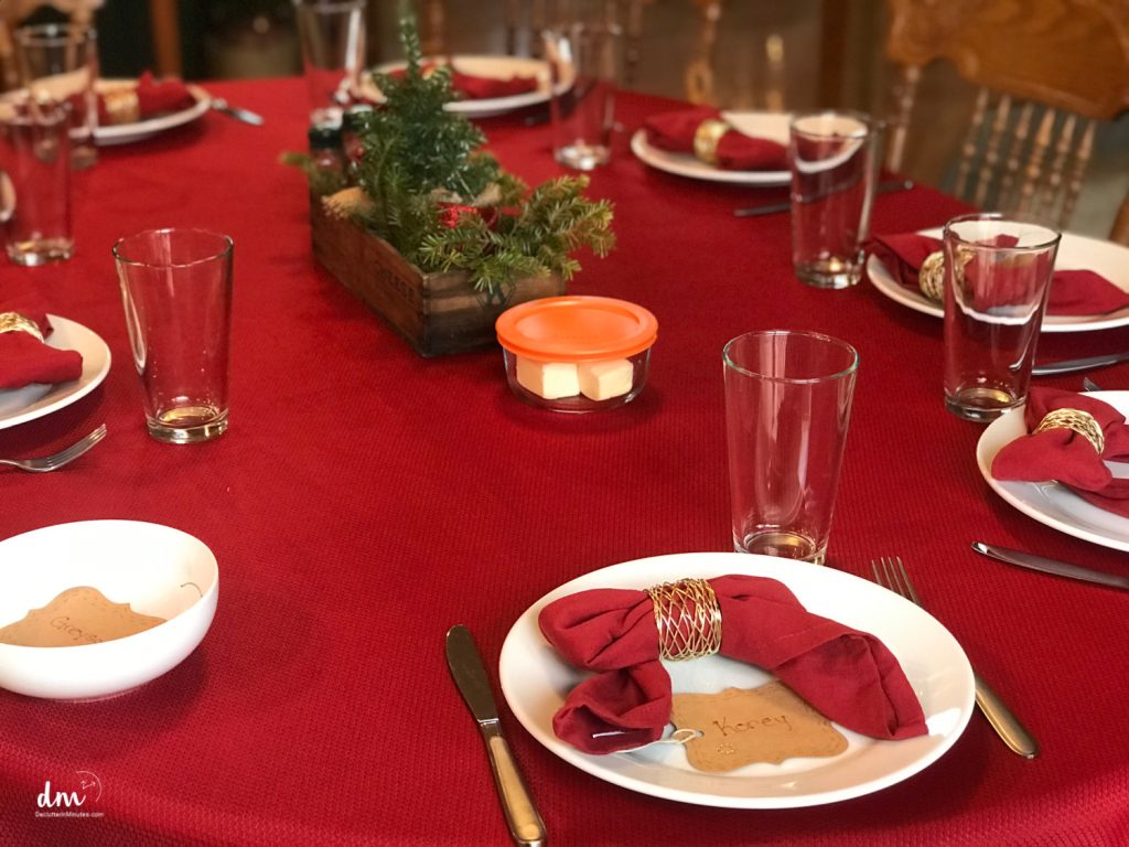 a red table with white plates and a small tree in the center for holiday dinner