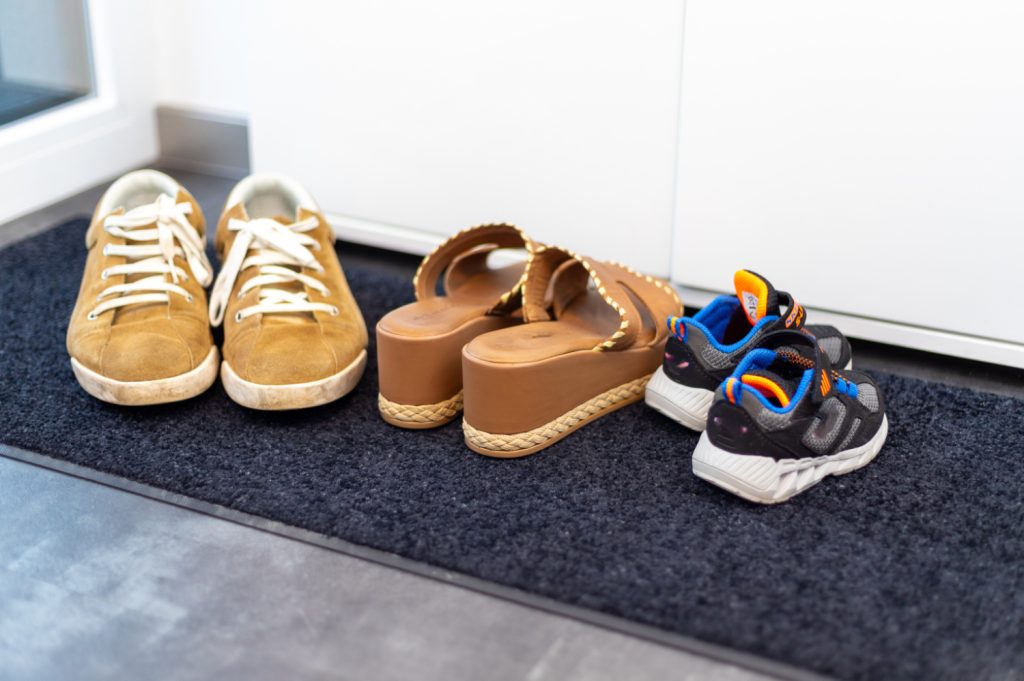 three pairs of shoes on a rug in a mudroom