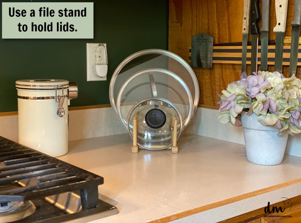 a file organizer holding lids on a counter in a small kitchen 