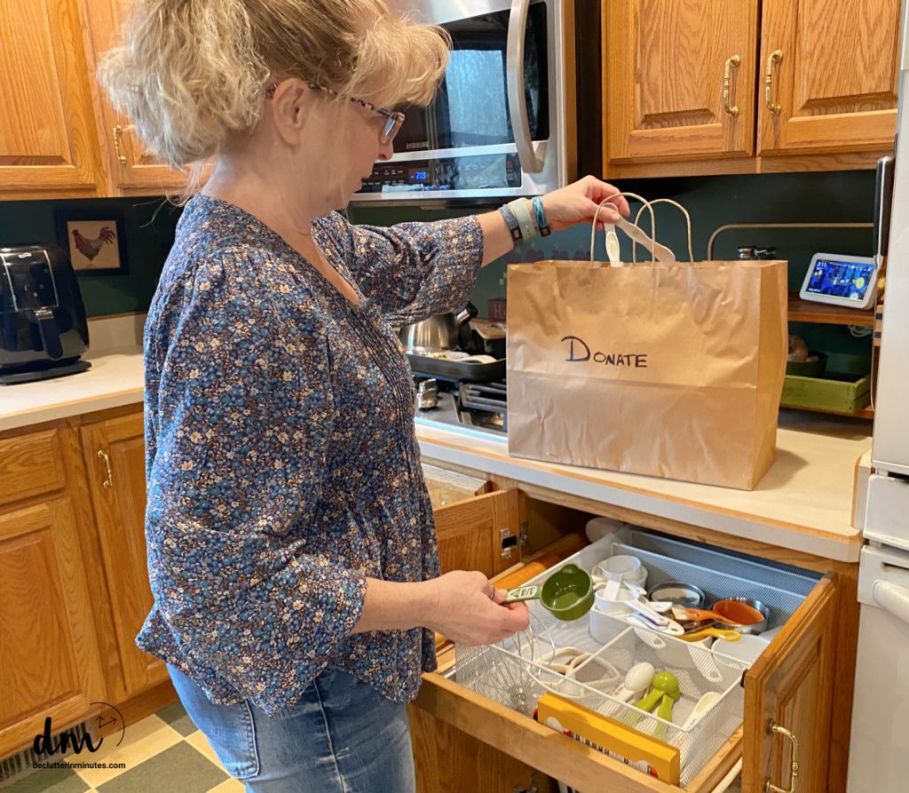 a woman putting measuring spoons into a donation bag