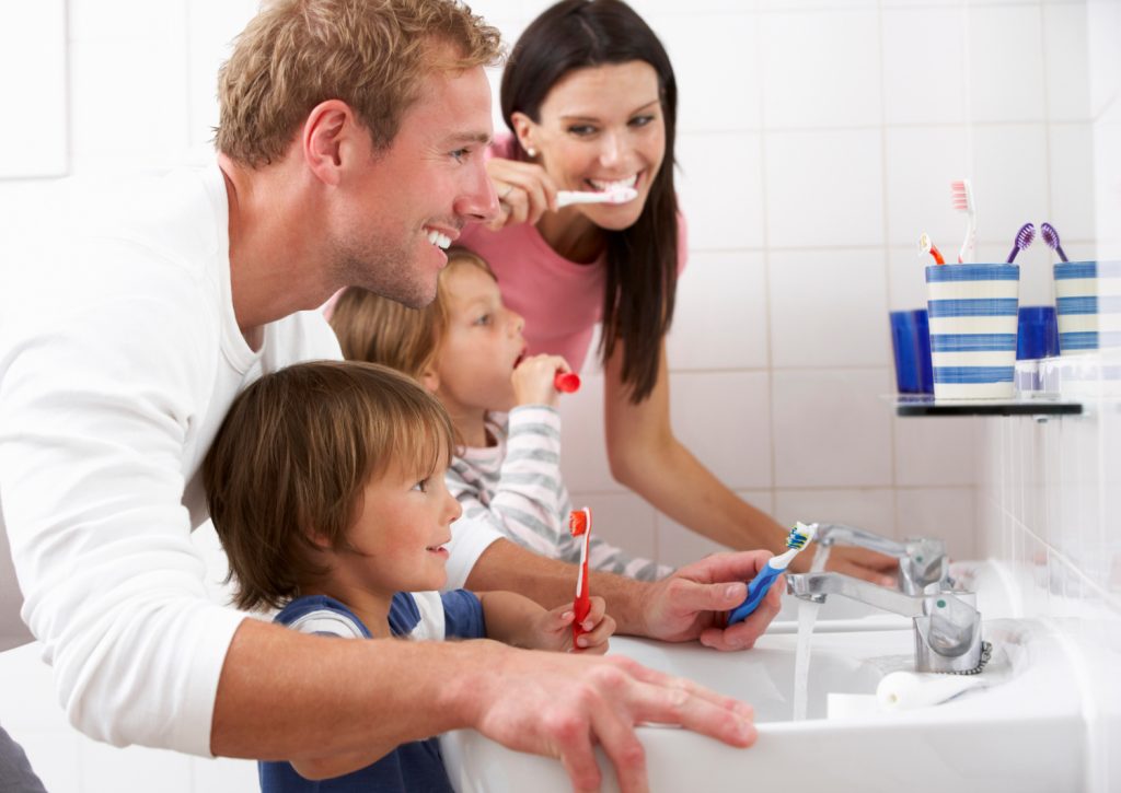 a young family brushing teeth in a bathroom 