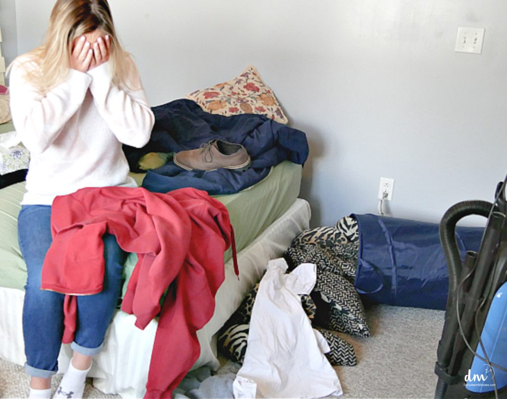 a young woman on a bed frustrated by the clutter in the room