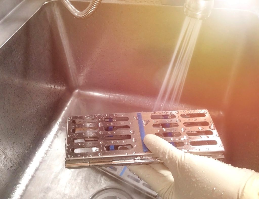 hands rinsing a tray from a fridge in the sink
