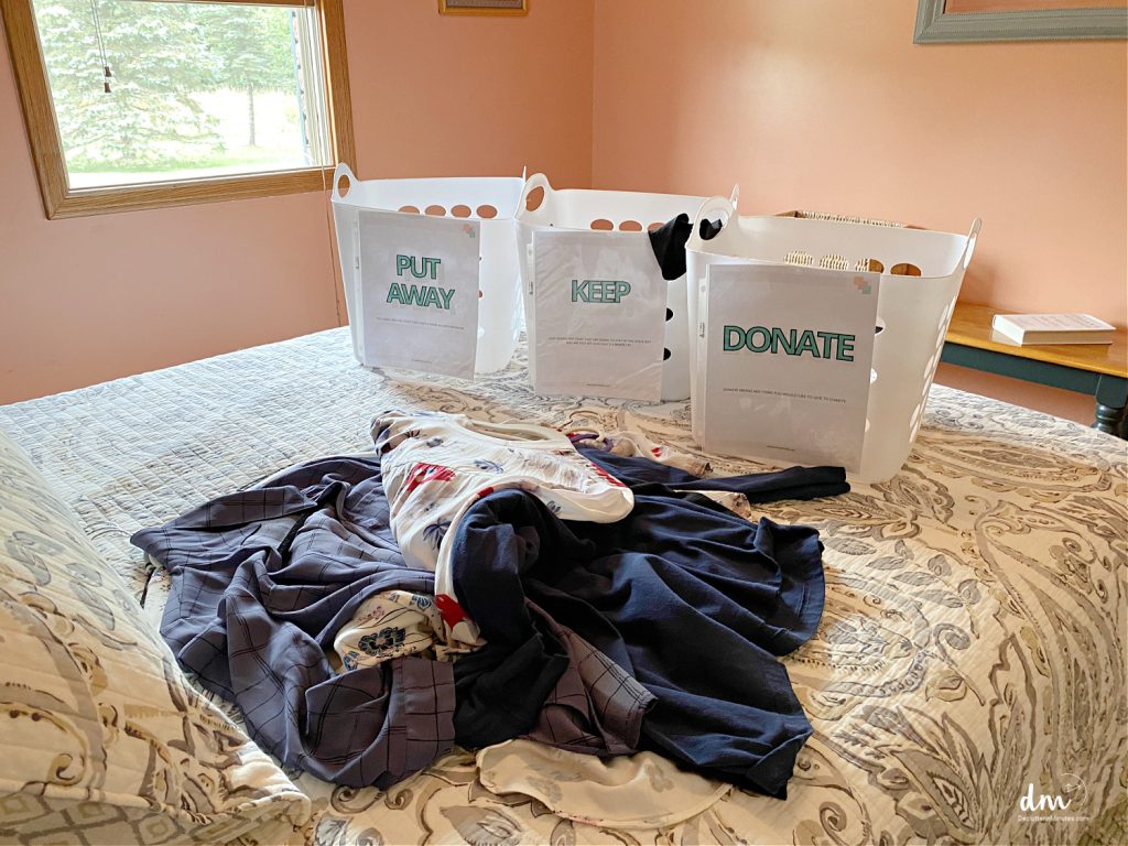 3 baskets on a bed near to clutter labeled for sorting