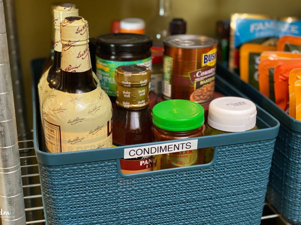 a basket of condiments and cans on a wire shelf