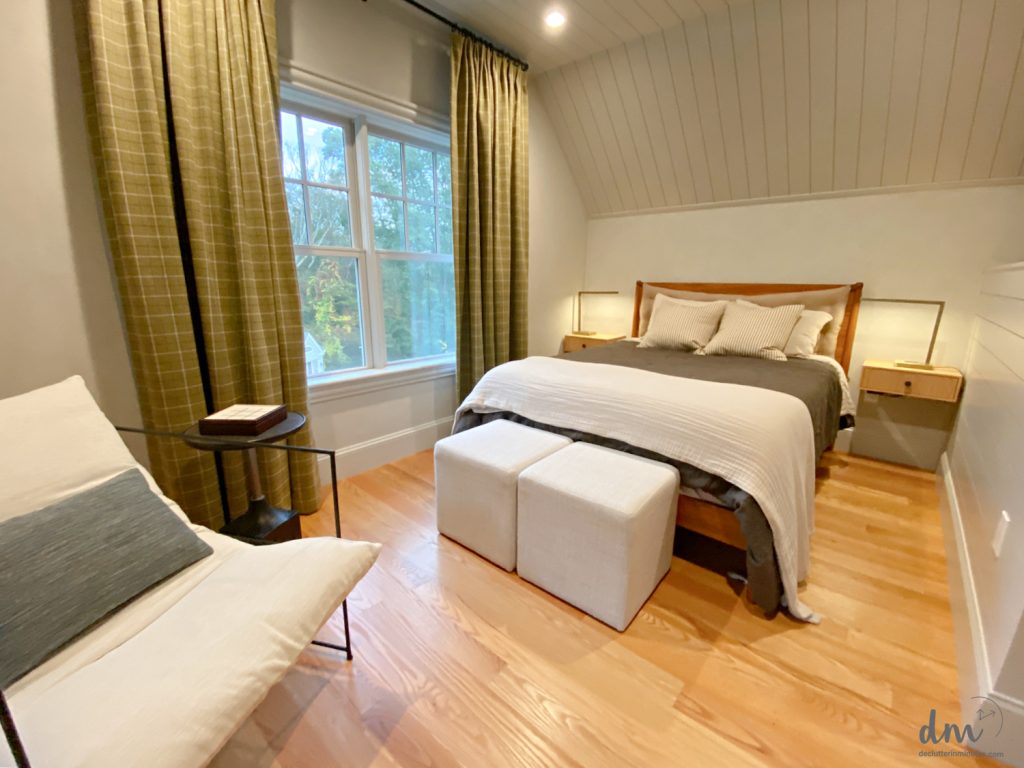 a chair near to a bed with storage ottomans at the foot