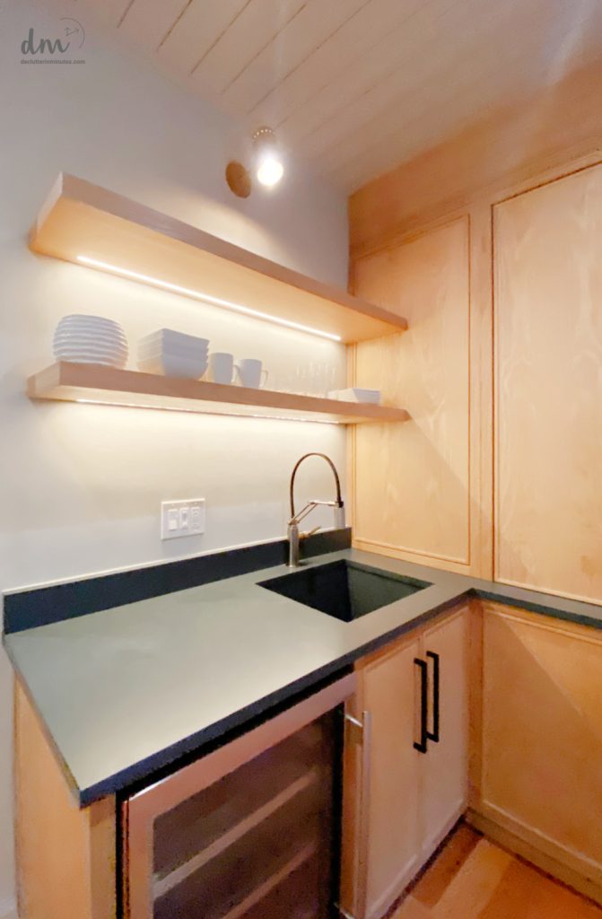 a small kitchen with dishes stored on shelves above a sink (1)