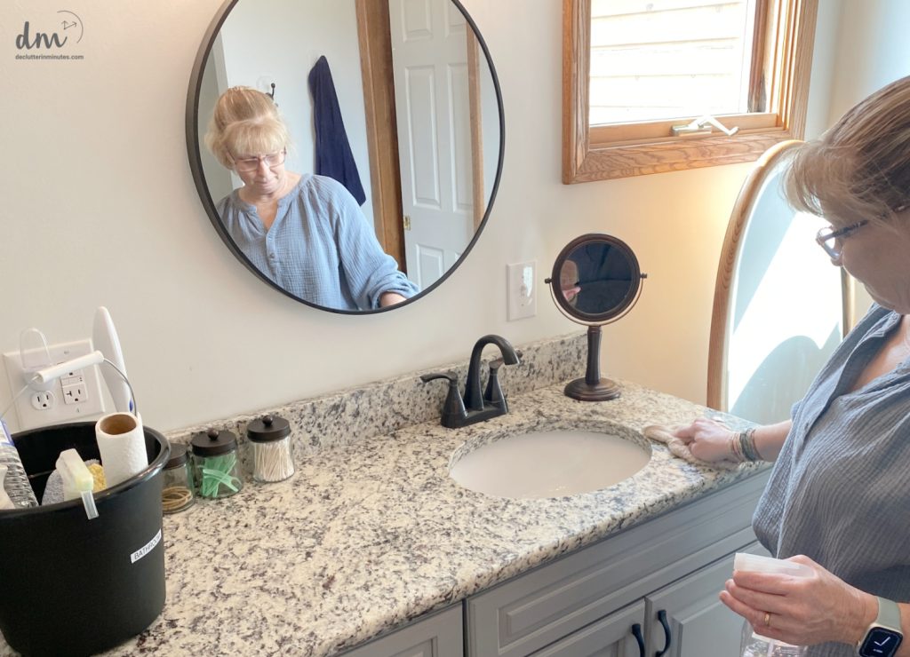 a woman wiping down a counter in a bathroom 