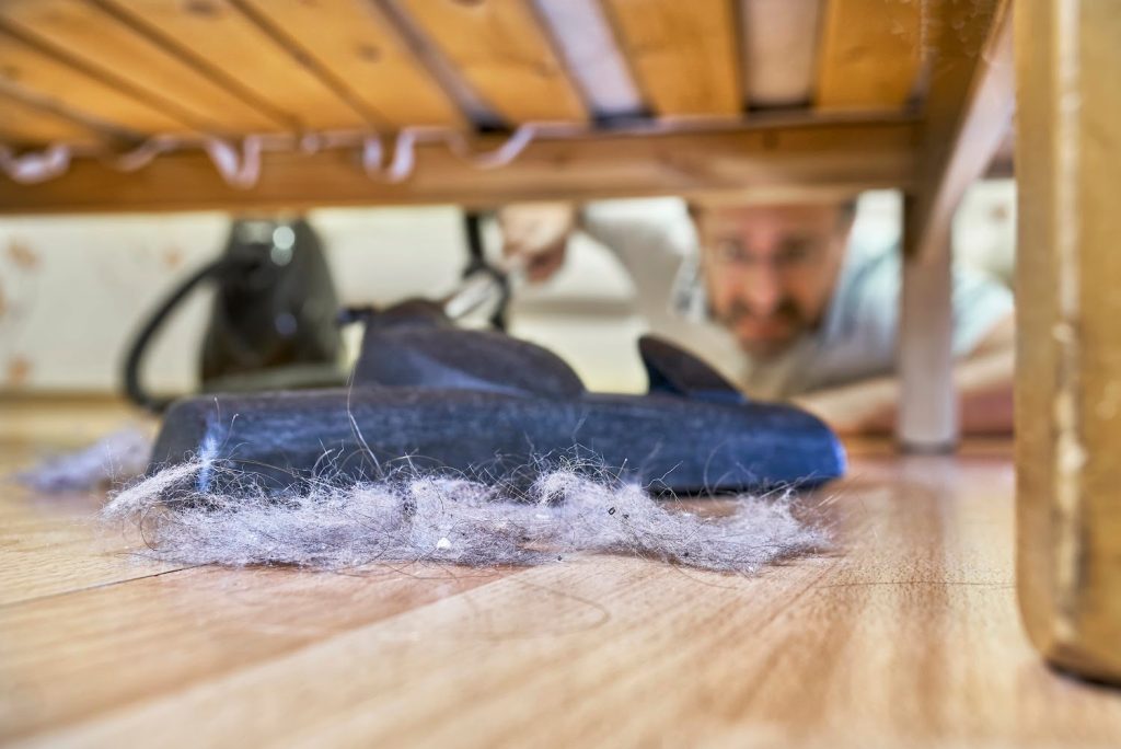 cleaning dust under a bed in a bedroom