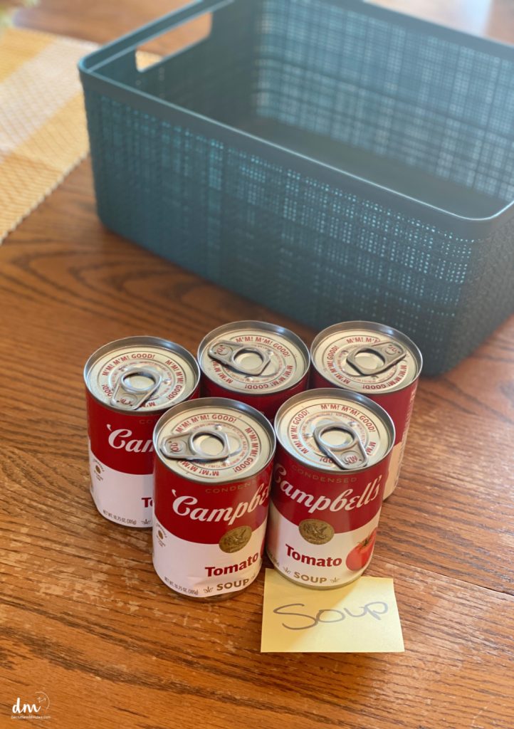 soup cans on a table next to a blue jute basket