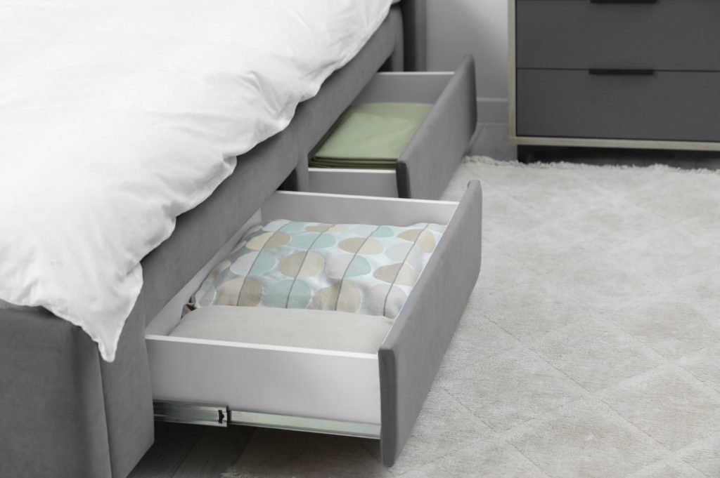 Storage drawers with bedding under modern bed in room