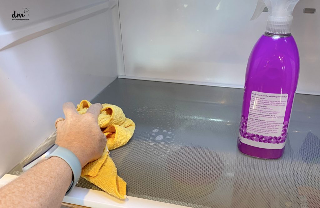 a hand cleaning a shelf with a yellow rag