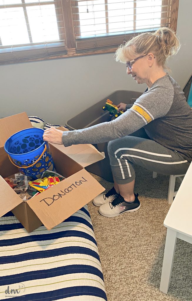 a woman putting toys into a donation box 