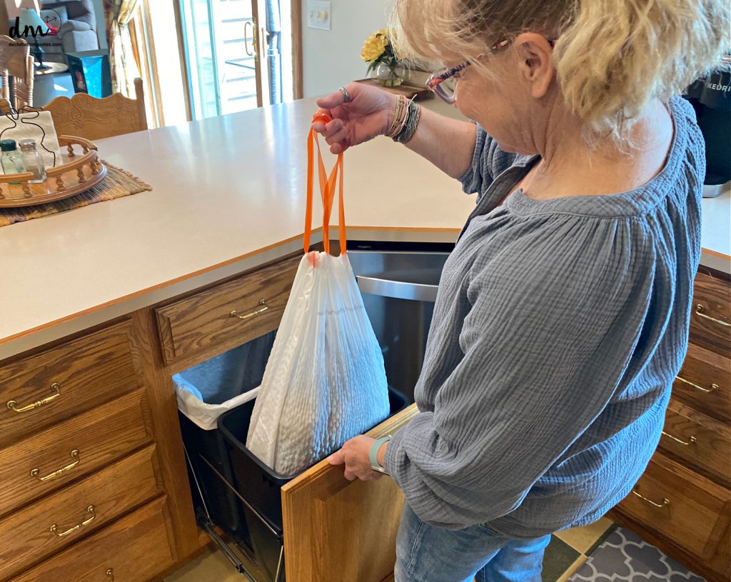 a woman taking out trash in a kitchen