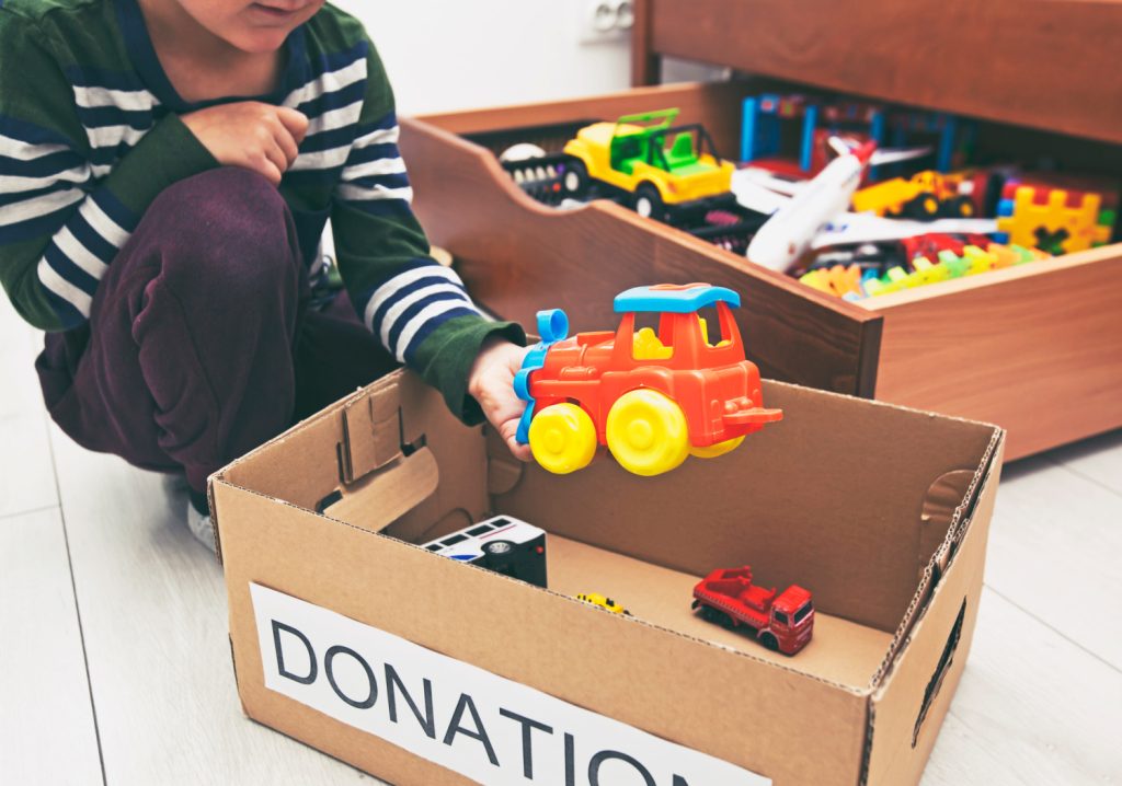 kid putting a toy into a donation box.