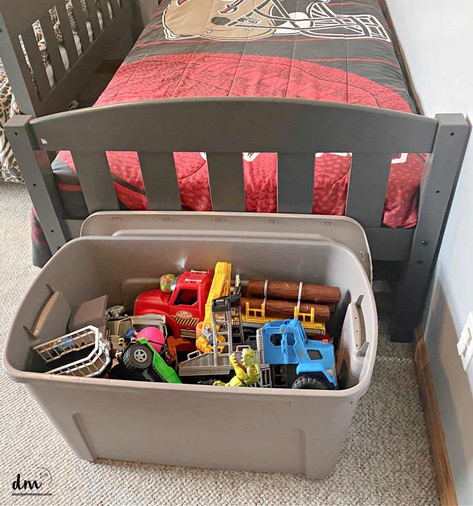 a bin of toys at the foot of a bed 