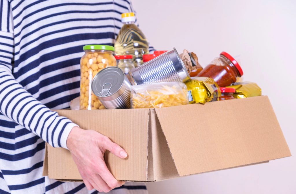 a woman holding a box of food for donation