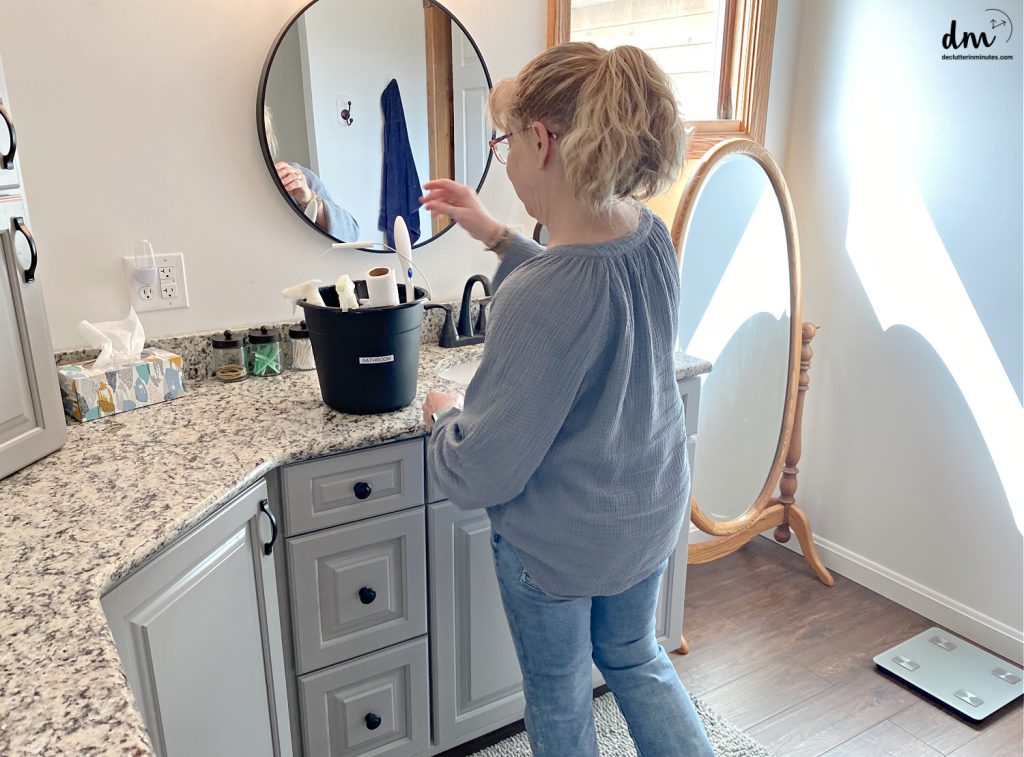 a woman in a bathroom with a black cleaning bucket