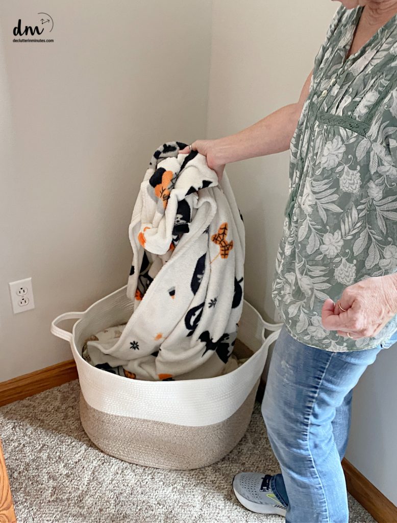 a woman putting blankets into a storage basket