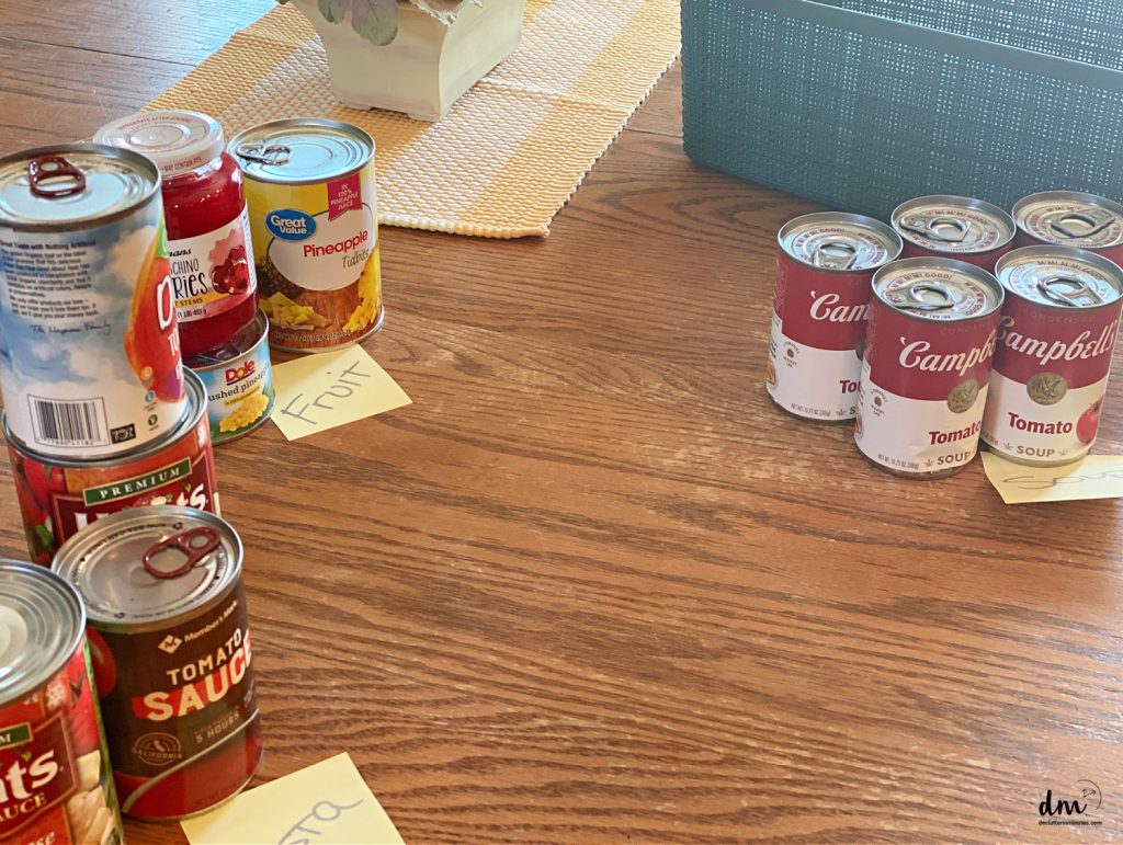 canned goods sorted out into categories on a kitchen table