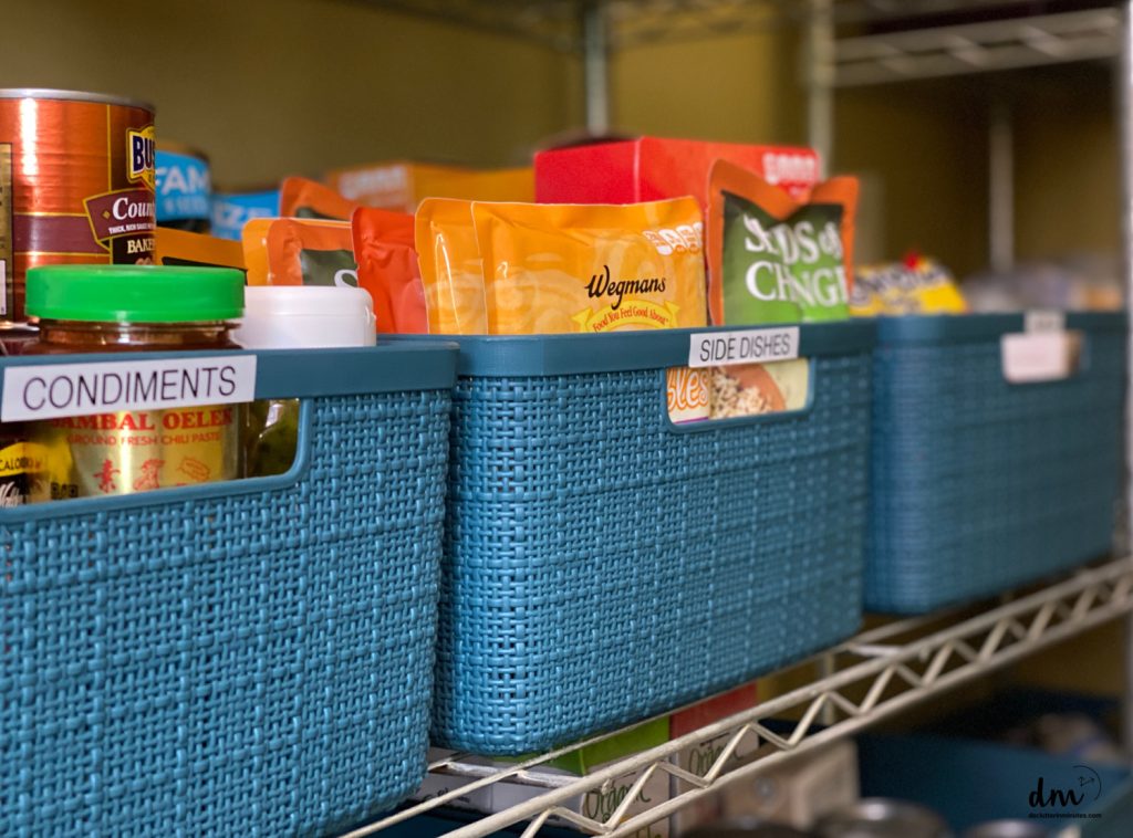 labeled blue baskets in a pantry that are filled with food