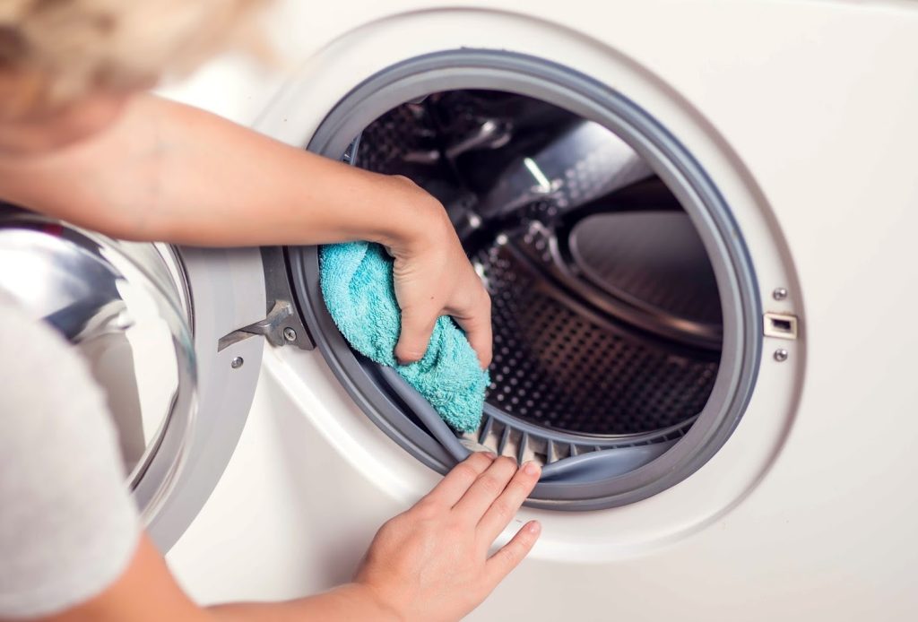 woman cleaning the seal of a front loading washing machine