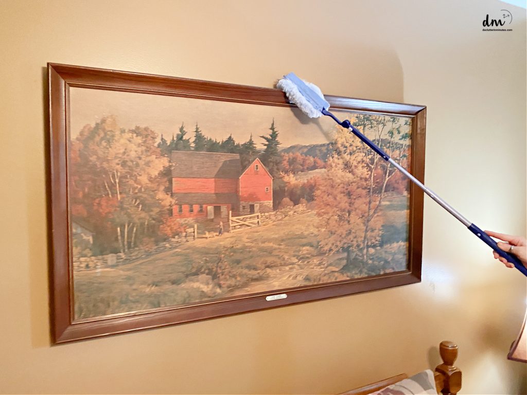 a duster cleaning a frame on a large picture in a room