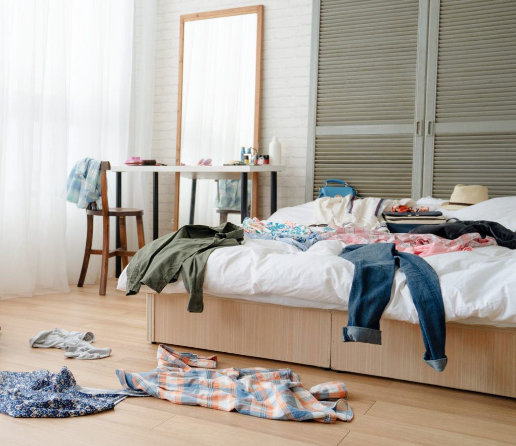 a messy bedroom with clothes on the floor and on a bed