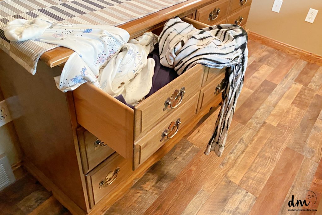 a messy dresser drawer with clothes spilling out