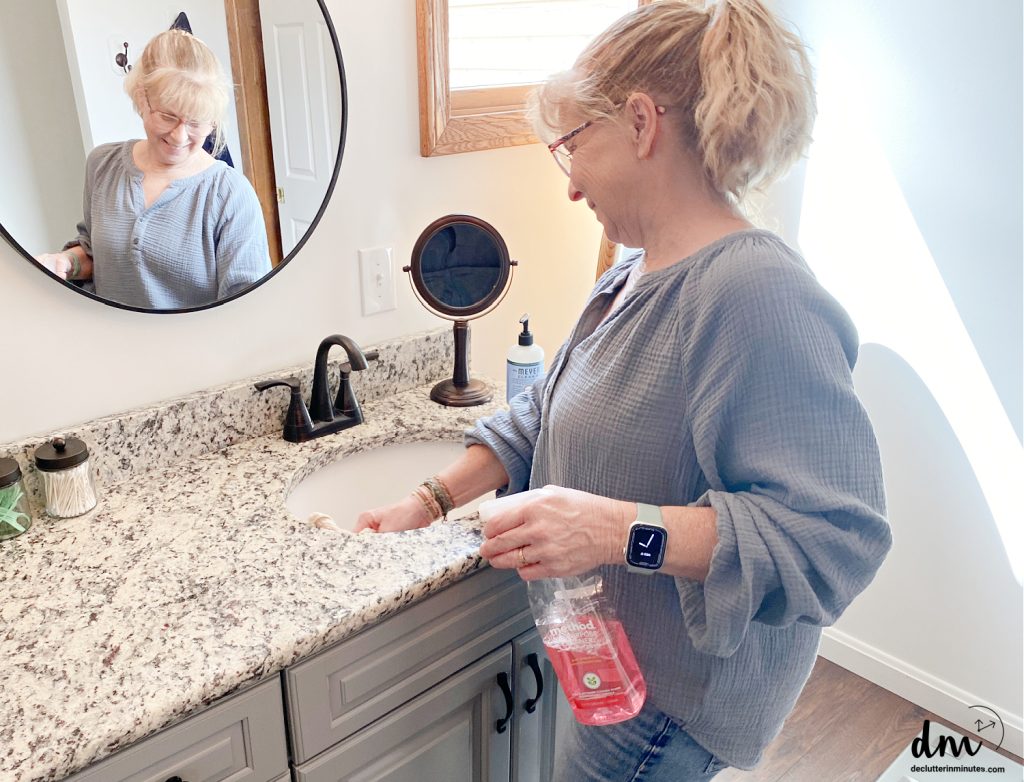 a woman cleaning a sink with cleaner in her hand