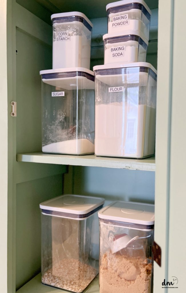 Storage bins that are labeled of baking supplies in a pantry