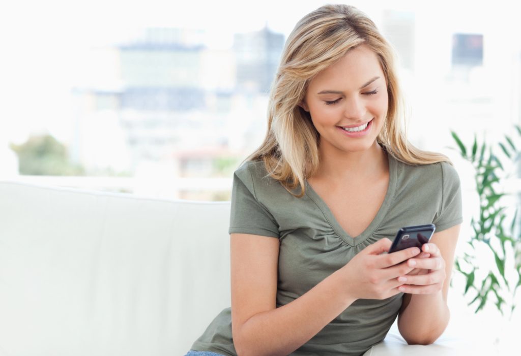 a young woman typing her cleaning list on her phone