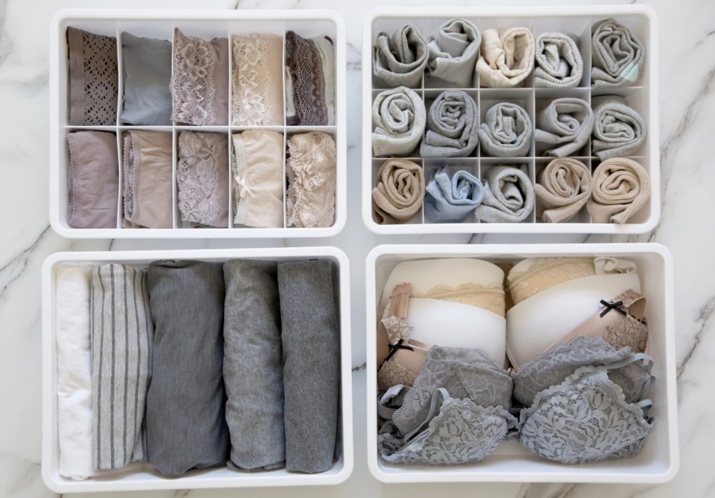 four containers of neatly folded clothes on a table